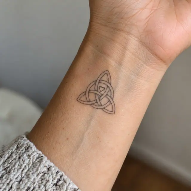 Fine-line trinity knot tattoo on the wrist